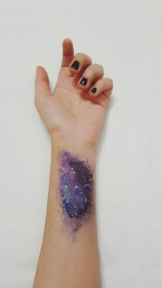 a woman's arm with a purple and blue tattoo on the left side of her wrist