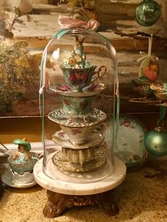 a glass clochet filled with tea cups and saucers on top of a table