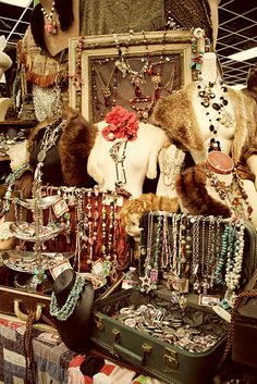 an assortment of necklaces and jewelry on display in a store with other items hanging from the ceiling