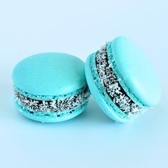 two blue macaroons with sprinkles on them are sitting next to each other