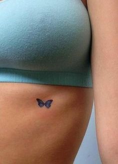 a woman's stomach with a small butterfly tattoo on the side of her belly