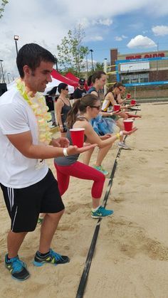 a group of people standing on top of a sandy beach holding red cups in their hands