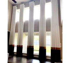 the sun shines through two white curtains in front of a window with black and brown trim