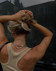 the back of a woman's head with tattoos on her upper arm and neck