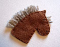 a brown and white horse brooch sitting on top of a white table next to a wall