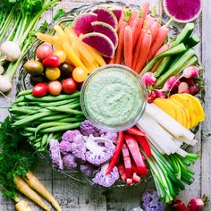 an assortment of fresh fruits and vegetables arranged on a table with a dip in the middle