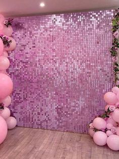 a room with pink balloons and flowers on the wall, in front of a purple sequin backdrop