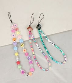 three necklaces with different designs on them sitting next to each other in front of a white wall