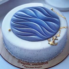 there is a blue and white cake with gold decorations on the top, sitting on a table