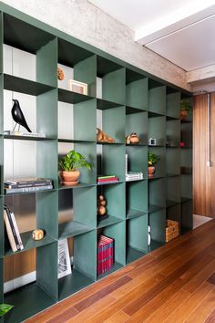 a room with green shelves filled with books and plants