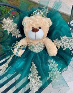 a teddy bear in a green dress sitting on a bench