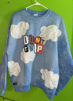 a blue sweatshirt with the words don't trip on it hanging up against a green wall