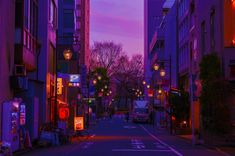 an empty city street at dusk with tall buildings on both sides and lit up by lanterns