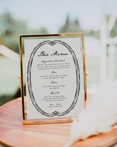 an elegant menu is displayed on a wooden table with white feathers in the foreground