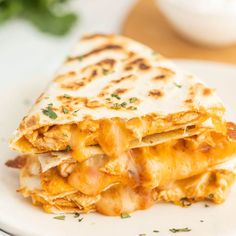 a white plate topped with a quesadilla cut in half on top of a table