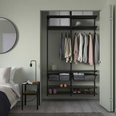 an open closet with clothes and shoes on the shelves next to a bed in a bedroom