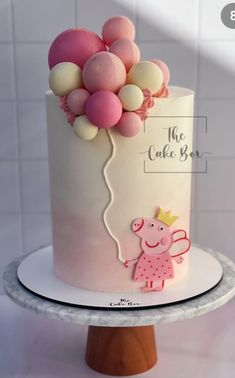 a white cake with pink and yellow balloons on top