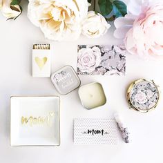 flowers and personalized items on a white surface with gold foil lettering that says mom