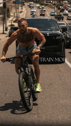 a man riding a bike down the middle of a street next to cars and trucks