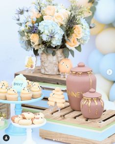 a table topped with cupcakes and cakes next to a vase filled with flowers