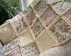 a quilted blanket sitting on top of a couch next to a potted plant