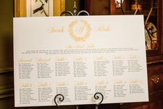 a wedding seating chart is displayed on a metal stand in front of a wooden cabinet