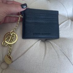 a person holding a black card case and a gold keychain