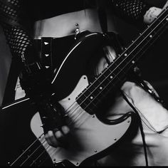 a woman in fishnet stockings holding a bass guitar