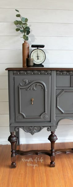 an old dresser painted gray and has a clock on top