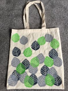 a tote bag with leaves on it sitting on the floor next to a carpet