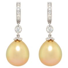 The golden pearl and diamond drop earrings feature two 15 x 13 mm pearls of fine quality nacre, splendid lustre, and intense golden color. The pearls are suspended from hoops set with round diamonds en pavé via two larger diamonds of 0.12 each. The total weight of diamonds is 0.55 carats. Our diamonds are of of top quality (color, clarity and cut, F/G-VVS). All of our pearls are untreated: they were extracted from Pinctada Maxima shells and their natural color and high luster have not been enhan Luxury Teardrop Pearl Earrings With Diamond Accents, Luxury Pear-shaped Pearl Drop Diamond Earrings, Luxury Briolette Pearl Drop Earrings, Luxury Pearl Drop Dangle Diamond Earrings, Luxury Teardrop Pearl Pendant Earrings, Luxury Teardrop Pearl Earrings With Pendant, Luxury Pear-shaped High Luster Pearl Earrings, Luxury High Luster Pear-shaped Pearl Earrings, Luxury Pearl Diamond Drop Earrings