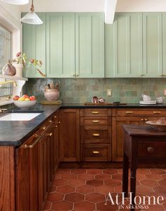 a kitchen with green cabinets and an island in front of the counter top is shown