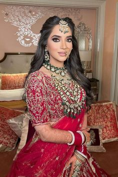 a woman in a red and gold bridal gown posing for the camera with her hands on her hips