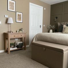 a bed room with a neatly made bed and a night stand next to the door