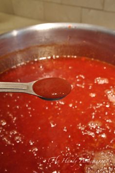 a ladle full of tomato sauce with meatballs on the side and a spoon in it