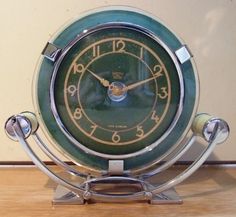 a green clock sitting on top of a wooden table