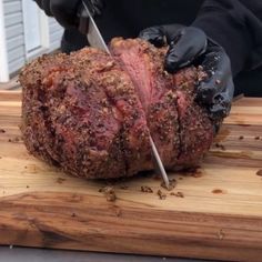 a person cutting meat with a knife on a wooden board