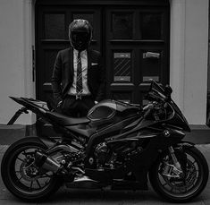 a man in a suit and tie standing next to a motorcycle