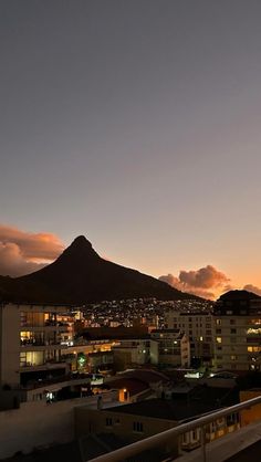 the sun is setting over some buildings and a mountain in the backgrouund