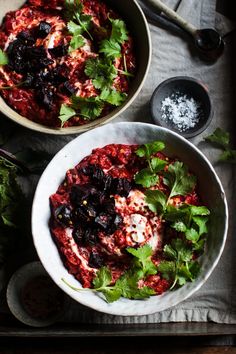 two bowls filled with food sitting on top of a table next to utensils