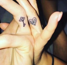 two people with tattoos on their fingers holding each other's hands and making the shape of a heart