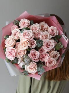 a woman holding a bouquet of pink roses