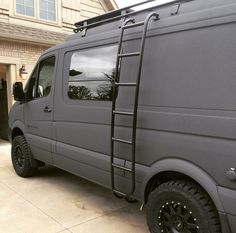 a grey van parked in front of a house with a ladder on the back door