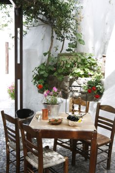 an outdoor table with chairs and potted plants