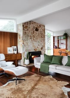 a living room filled with furniture and a fire place next to a stone faced wall