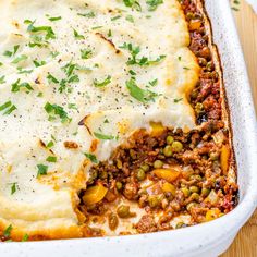 a casserole dish filled with meat, vegetables and gravy topped with parmesan cheese