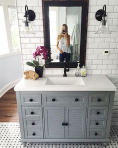 a bathroom with a sink, mirror and flowers on the counter in front of it