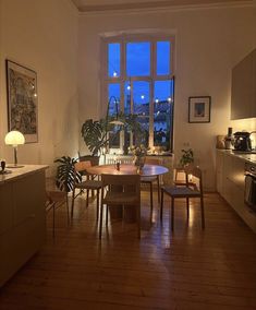 a dining room table and chairs in front of a window with the city lights outside