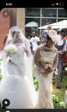 two women in wedding dresses walking down the aisle