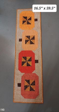 a quilted table runner with four oranges and bows on the top, along with two smaller ones